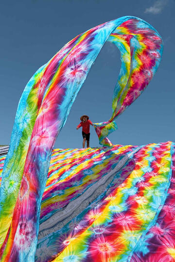 The Rainbow Batik factory worker tossing fabric to dry in the sun © Roberto Pazzi
