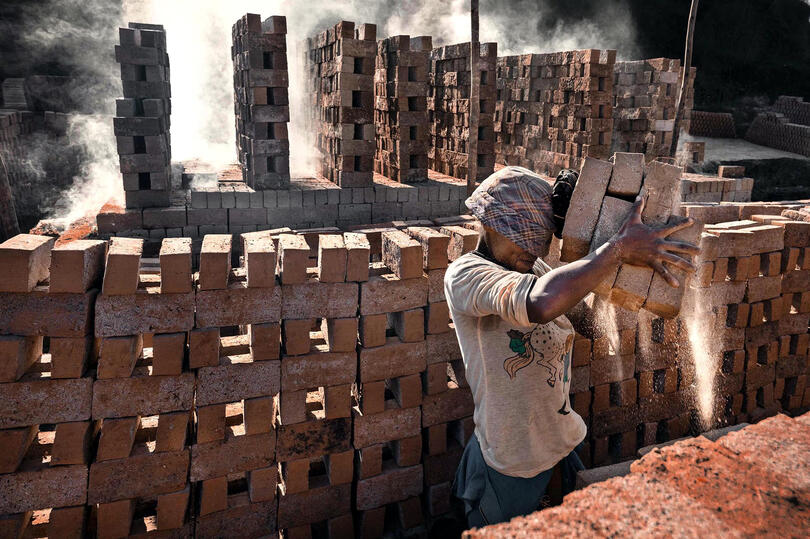 The Hell of Clay Portrait of a brick factory worker framed by rows of bricks © Roberto Pazzi