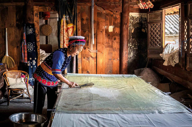 Batik Bai woman working on indigo-dyed batik textiles in her workshop © Roberto Pazzi