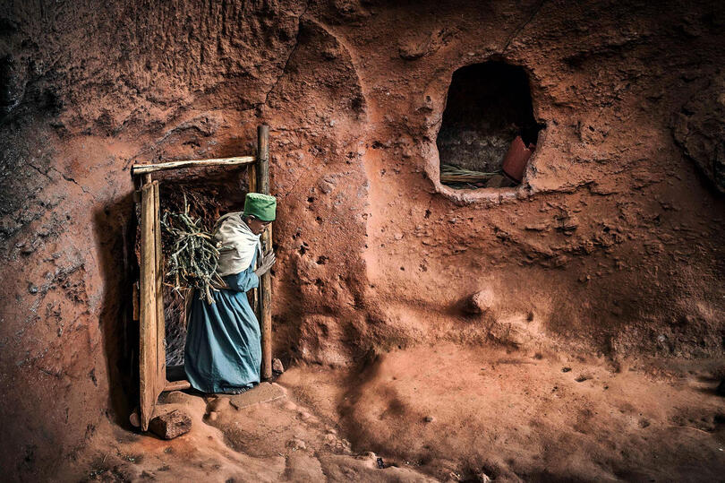 Secret Passage Woman carrying a daily load of firewood for heating inside one of the rock-hewn monolithic churches in Lalibela Buy Print