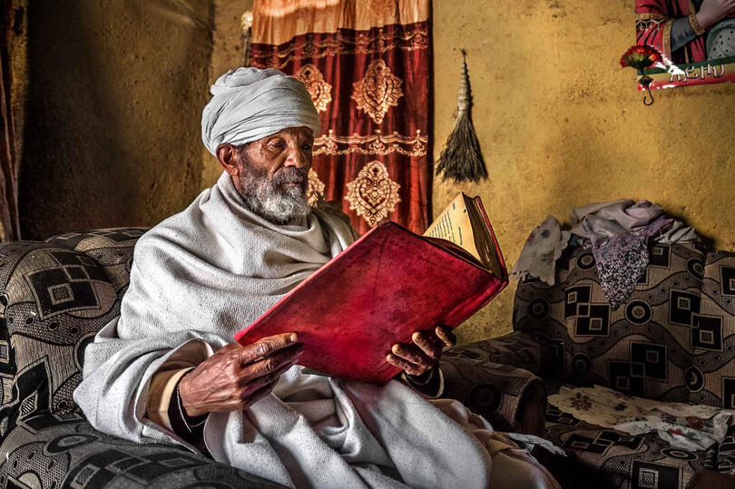 The Holy Book Portrait of an Orthodox priest reading a holy book in his house Buy Print