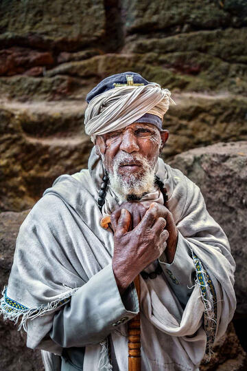 Clinging to Faith Portrait of an Orthodox priest in one of the eleven rock-hewn monolithic churches in Lalibela Buy Print